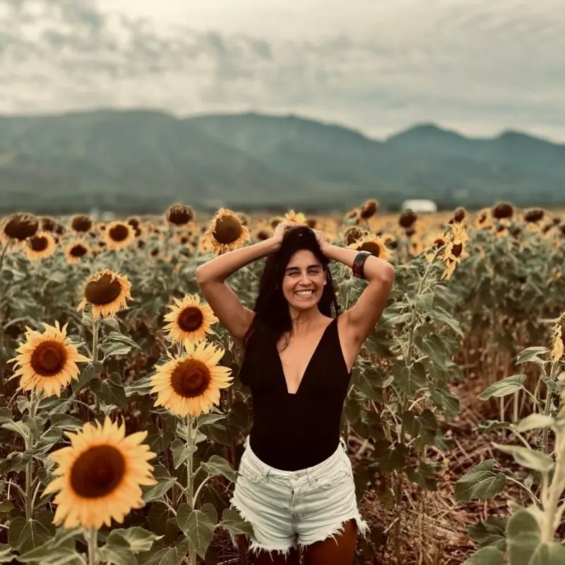 Daniela laughing in a field of sunflowers, mountains in the background