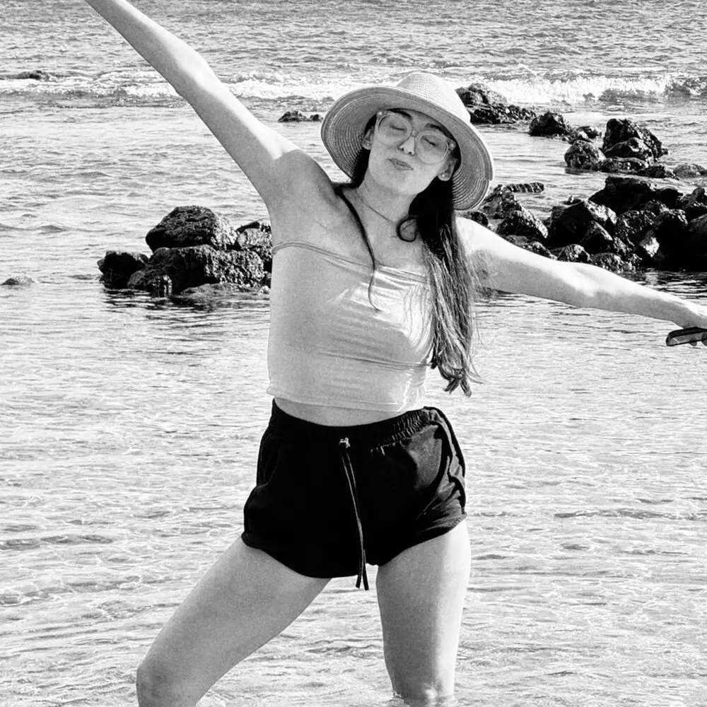 Black-and-white photo of Daniela celebrating on the beach, arms in the air